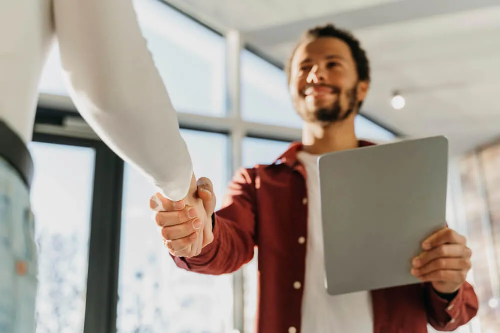 Empresário cumprimenta parceiro com aperto de mãos, simbolizando confiança e parcerias estratégicas no modelo de full commerce.