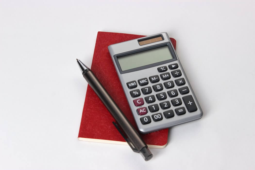 Calculadora sobre caderno, com caneta ao lado.