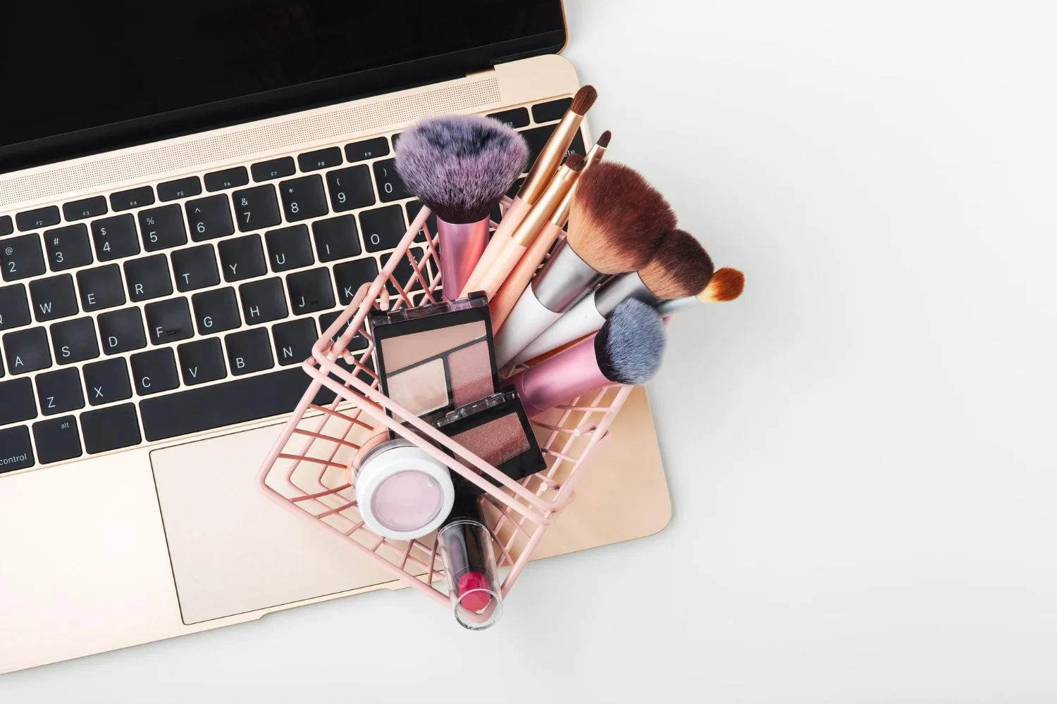 Carrinho com pincéis de maquiagem em cima do notebook, representando as vendas no marketplace Beleza na Web