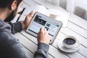 Homem lendo um site de notícias, por meio de um tablet, que conta com retail media