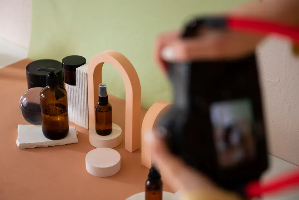 Fotografia de frascos de cosméticos sendo registrada com câmera profissional, ilustrando a produção de imagens para vender produtos de beleza online.