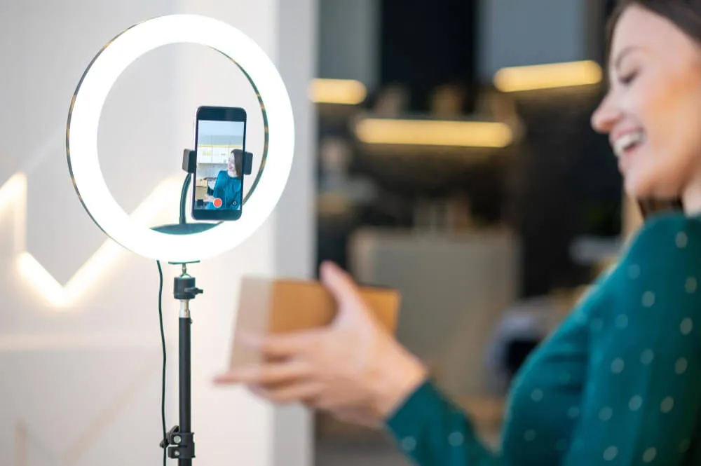Mulher apresenta um produto diante do celular e ring light durante uma live no TikTok Shop.